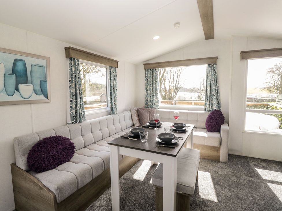 A living room with a sofa and dining table at Standard Caravan at Three Lochs Holiday Park, Newton Stewart