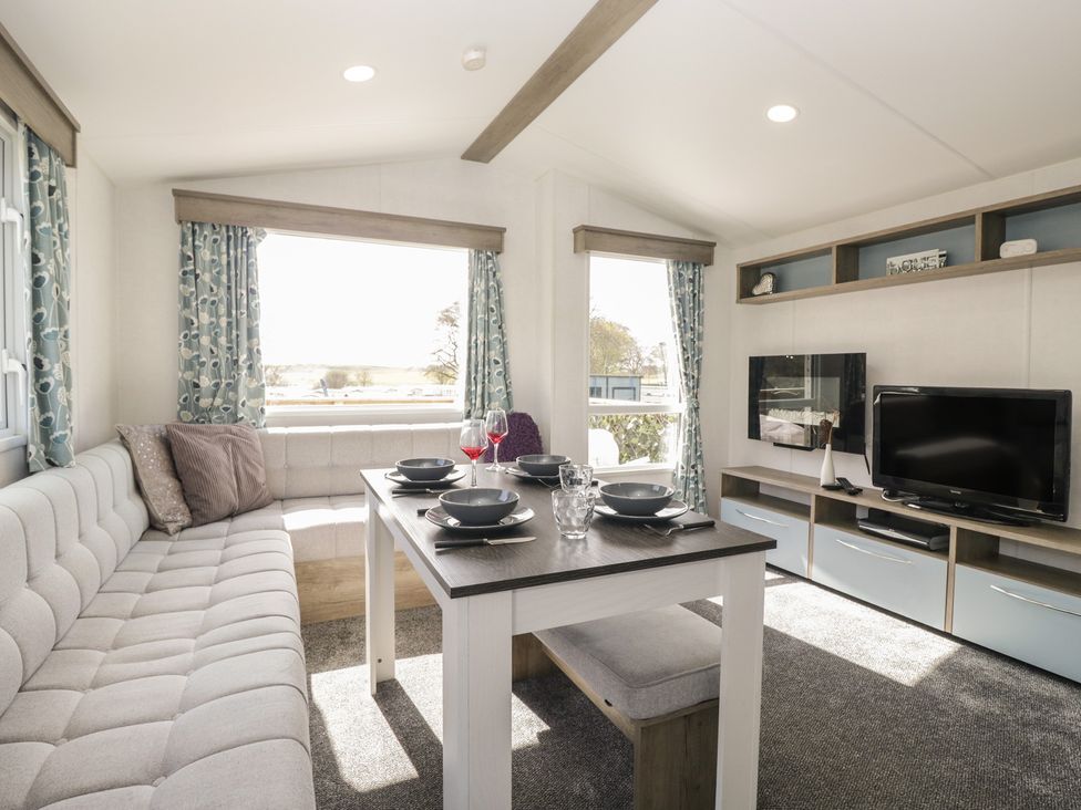 A living room with a dining table and sofa at Standard Caravan at Three Lochs Holiday Park in Newton Stewart