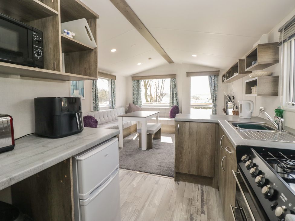 A kitchen with appliances and dining area at Standard Caravan at Three Lochs Holiday Park, Newton Stewart