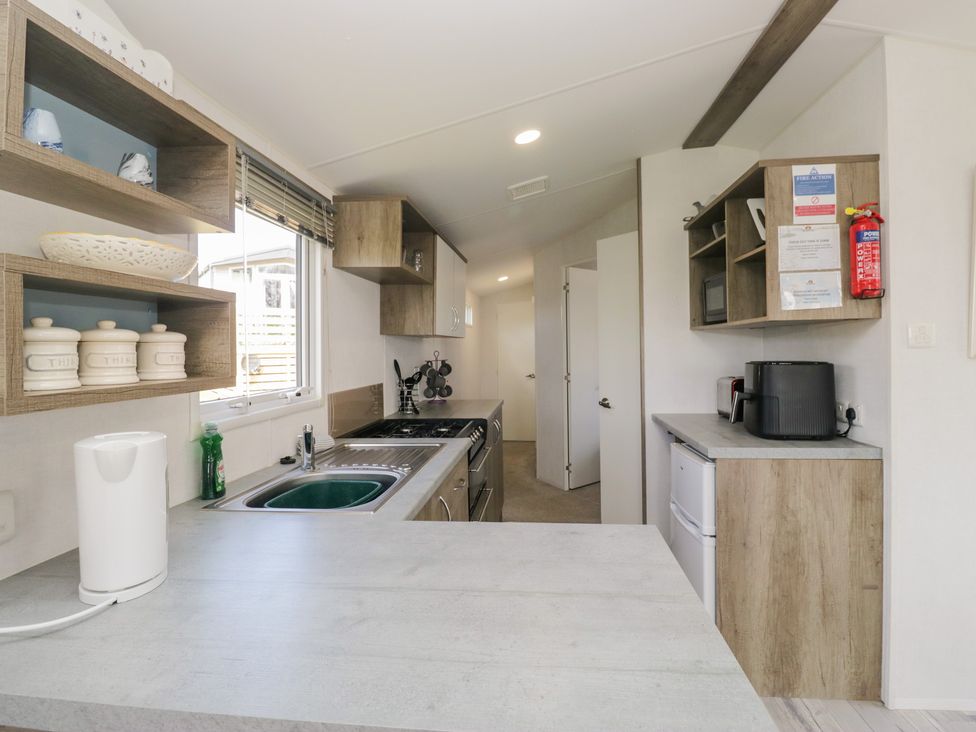 A kitchen with a sink, oven, and refrigerator at Standard Caravan at Three Lochs Holiday Park Newton Stewart