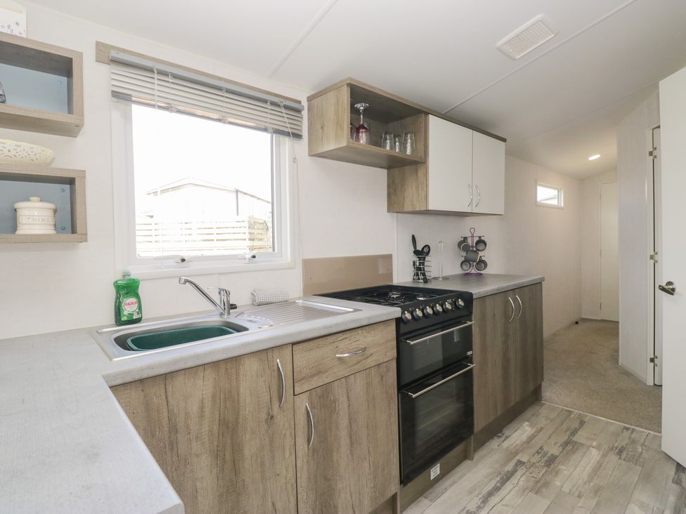 A kitchen with a sink and cooking range at Standard Caravan at Three Lochs Holiday Park in Newton Stewart