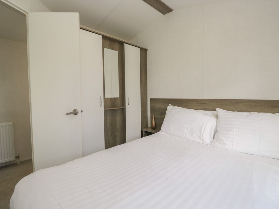 A bedroom with a bed and wardrobe at Standard Caravan at Three Lochs Holiday Park, Newton Stewart