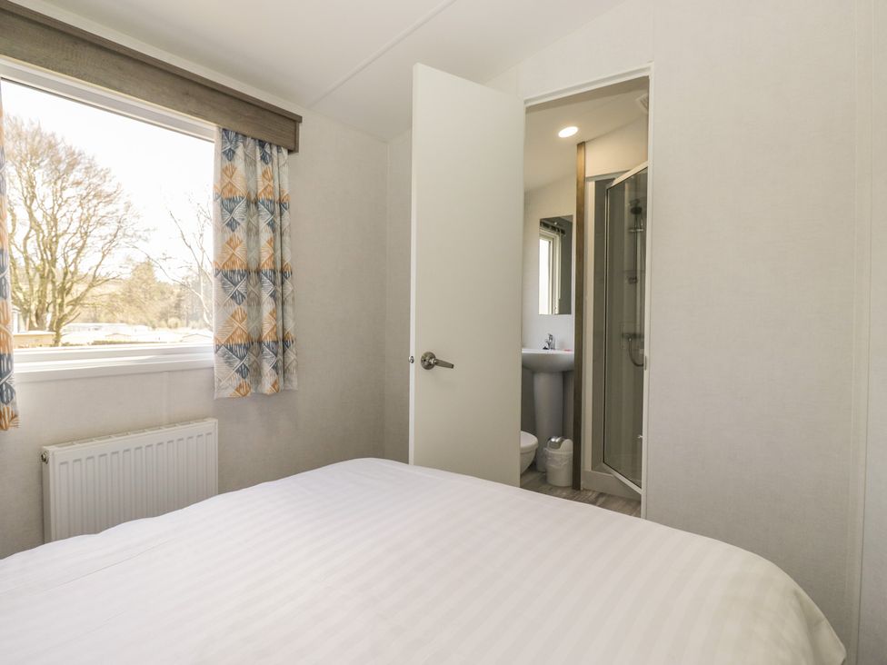 A bedroom with a bed and a bathroom view at Standard Caravan at Three Lochs Holiday Park Newton Stewart