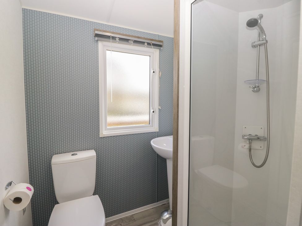 A bathroom with a shower and a toilet in Standard Caravan at Three Lochs Holiday Park Newton Stewart