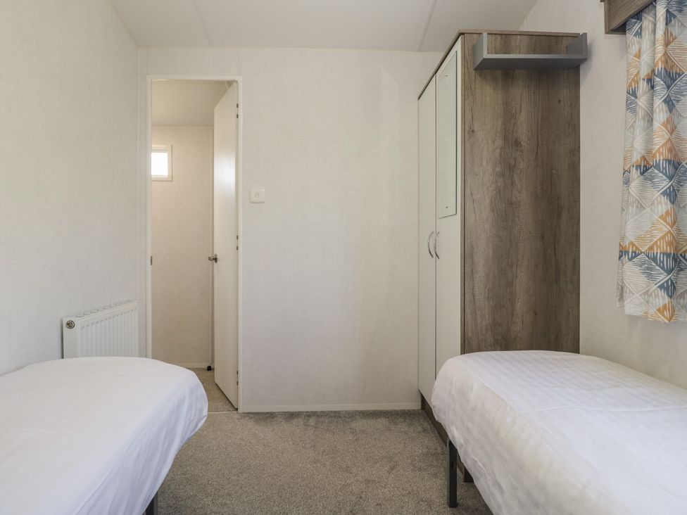 A bedroom with two beds and a wardrobe at Standard Caravan at Three Lochs Holiday Park, Newton Stewart