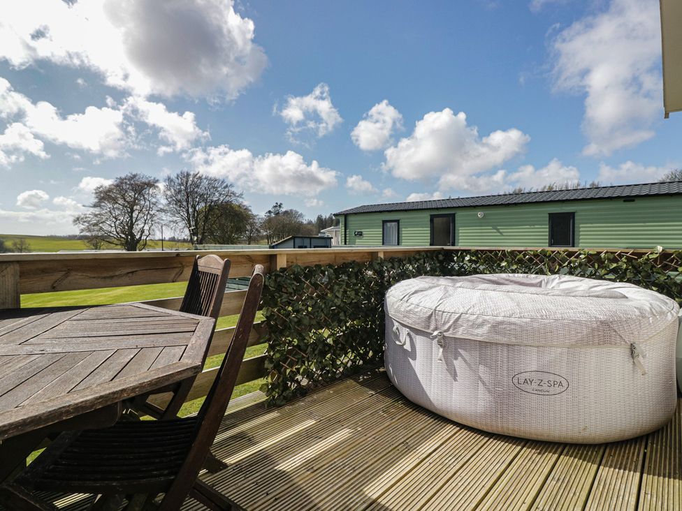 An outdoor area with a hot tub and seating at Standard Caravan at Three Lochs Holiday Park Newton Stewart