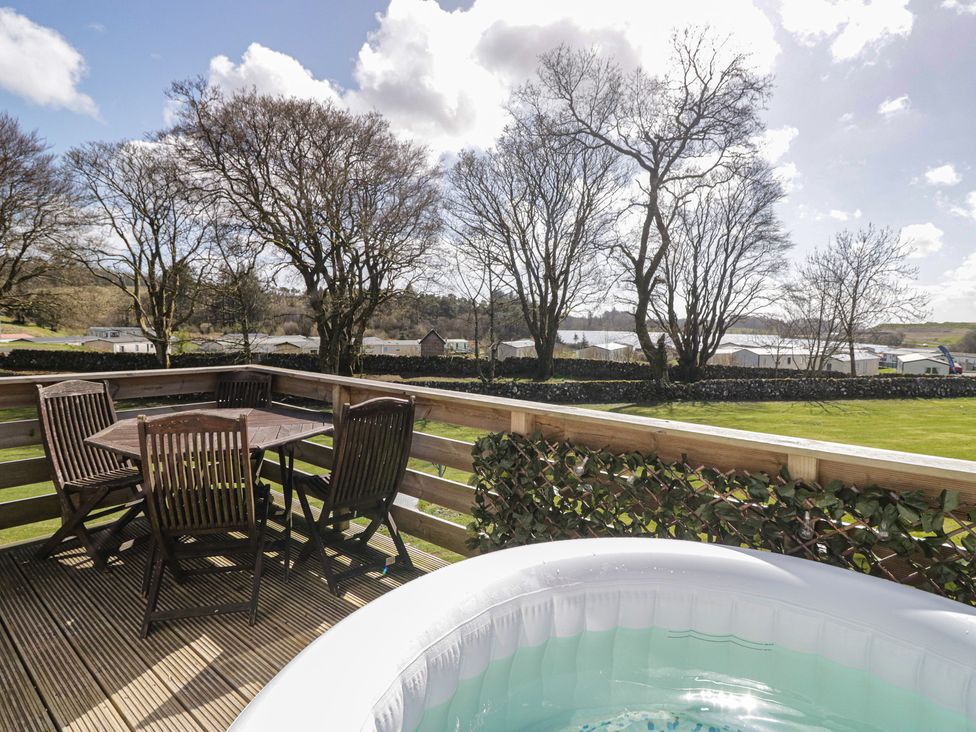 An outdoor area with a hot tub and a table with chairs at Standard Caravan at Three Lochs Holiday Park, Newton Stewart