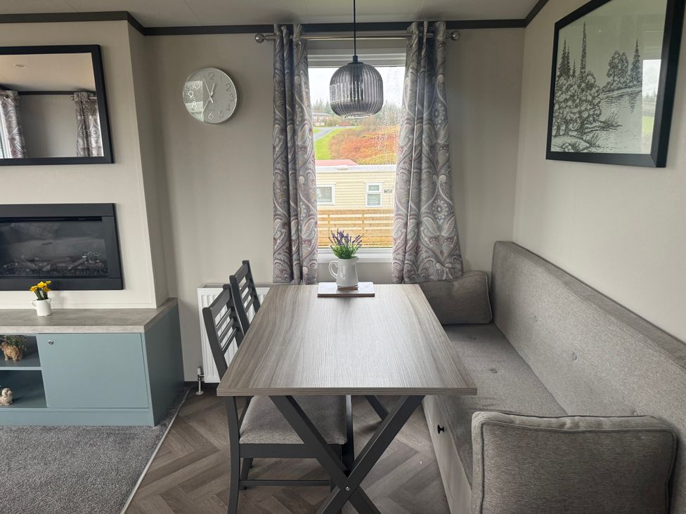 A dining room with a gray table and sofa at Lochwood Platinum Superior at Three Lochs Holiday Park Newton Stewart