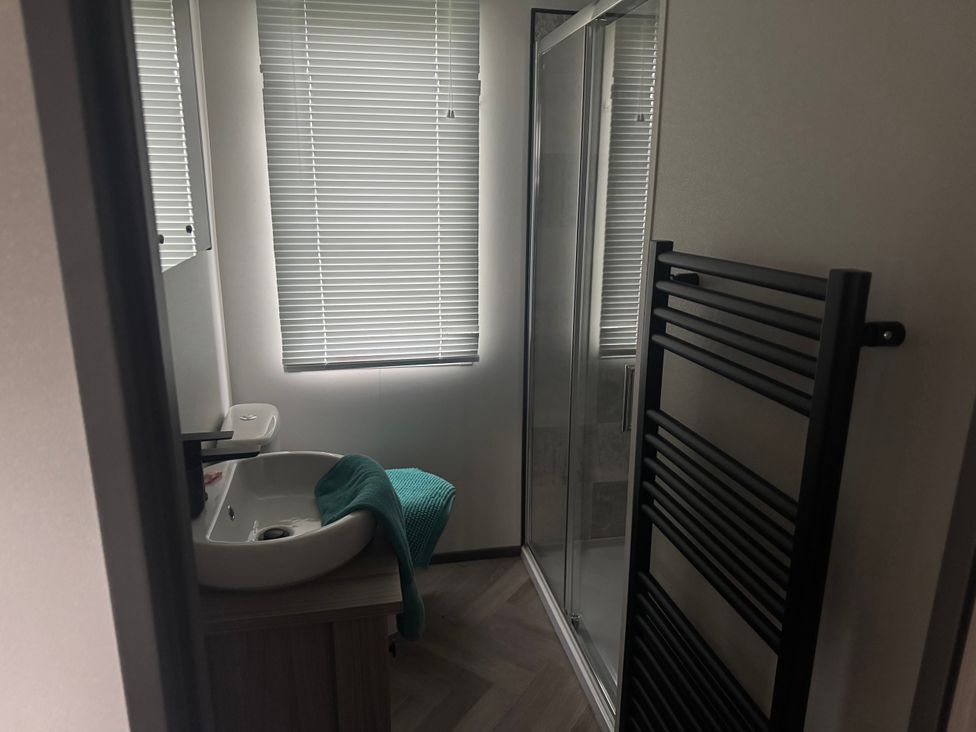 A bathroom with a wash basin and shower at Lochwood Platinum Superior at Three Lochs Holiday Park, Newton Stewart