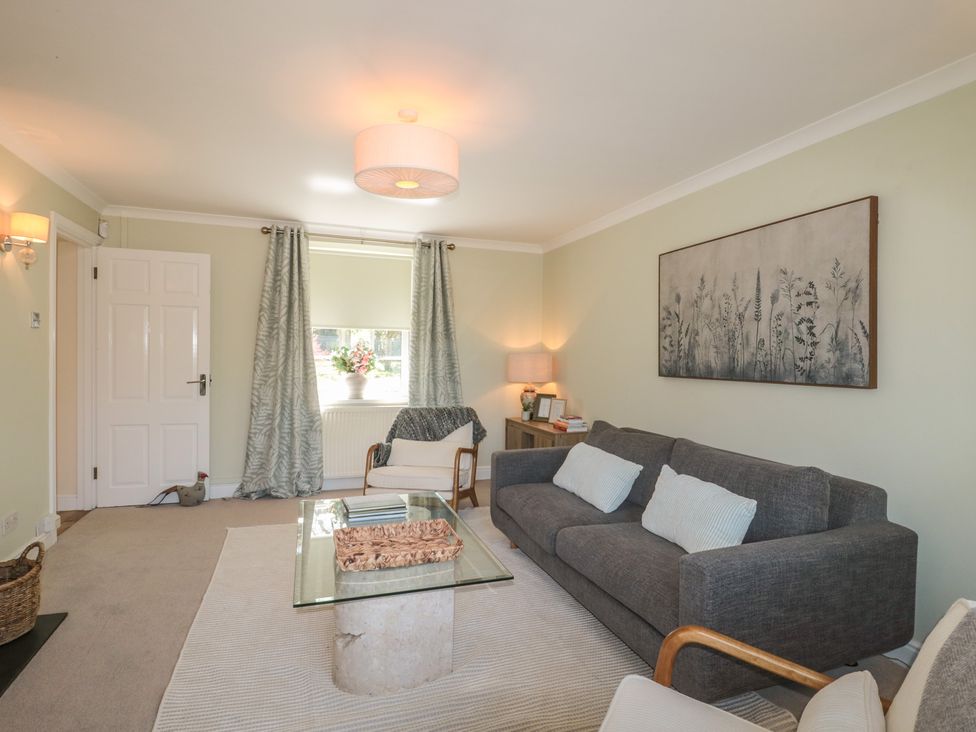 A living room with a sofa, coffee table, and lamp at The Little Vicarage in Highbridge