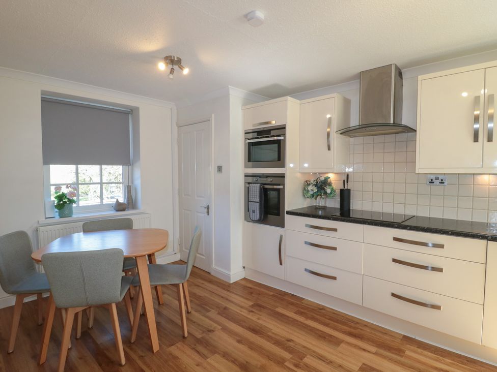 A kitchen with a dining table and oven at The Little Vicarage in Highbridge