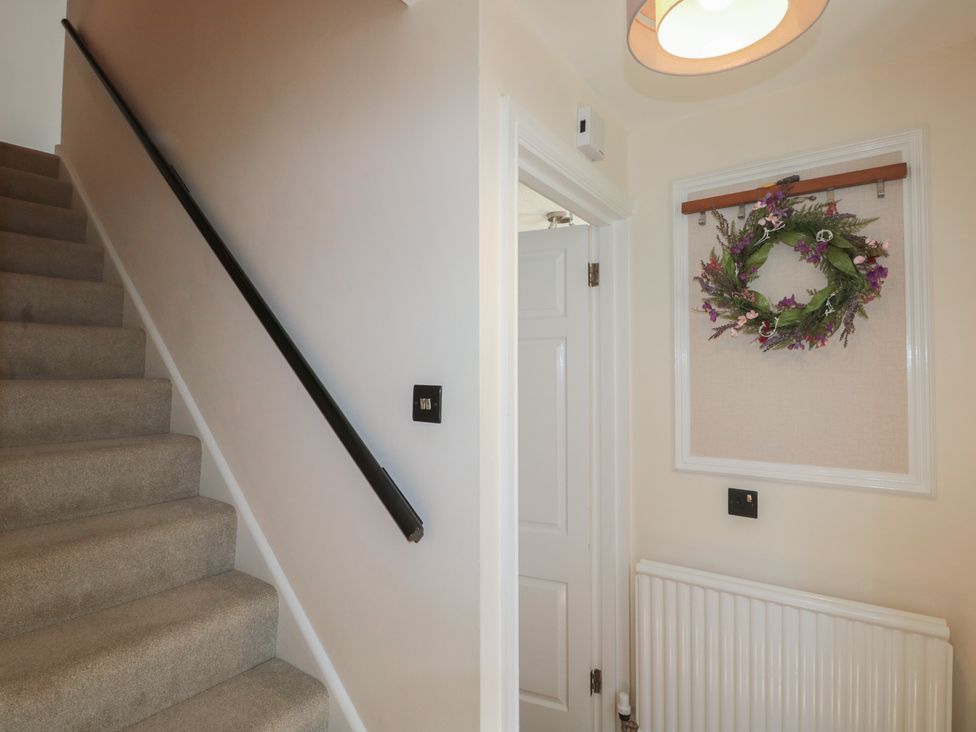 A hallway with stairs and a wreath on the wall at The Little Vicarage in Highbridge