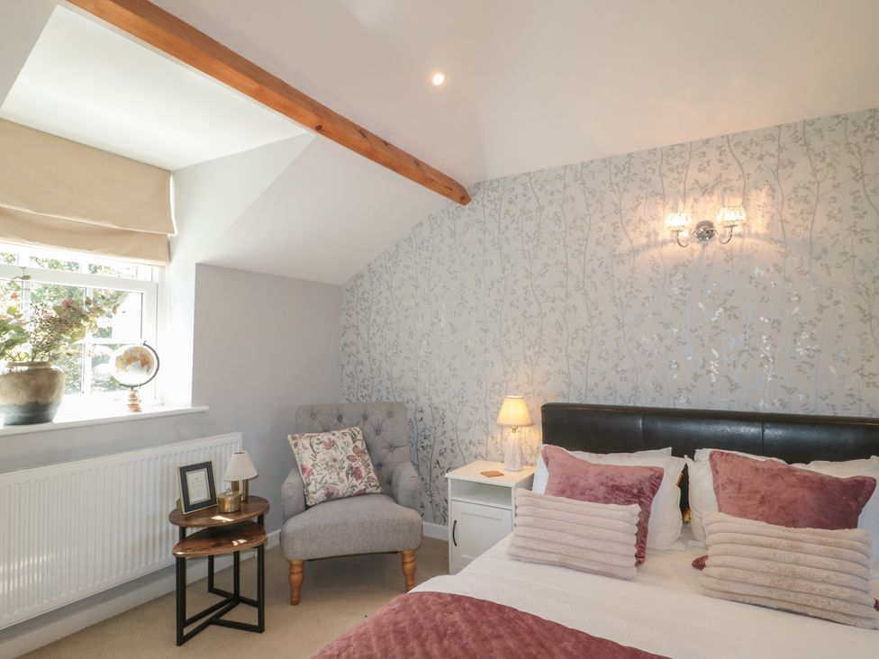 A bedroom with a bed and a chair at The Little Vicarage in Highbridge