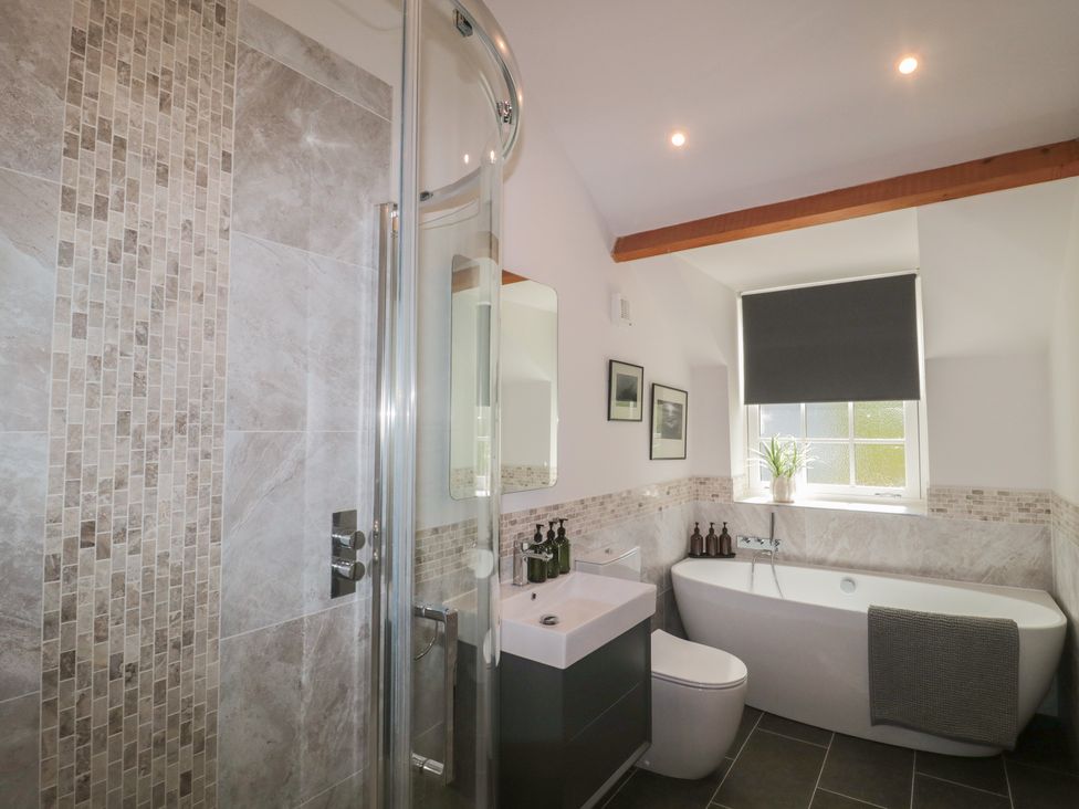 A bathroom featuring a shower, bathtub, toilet, and sink at The Little Vicarage in Highbridge