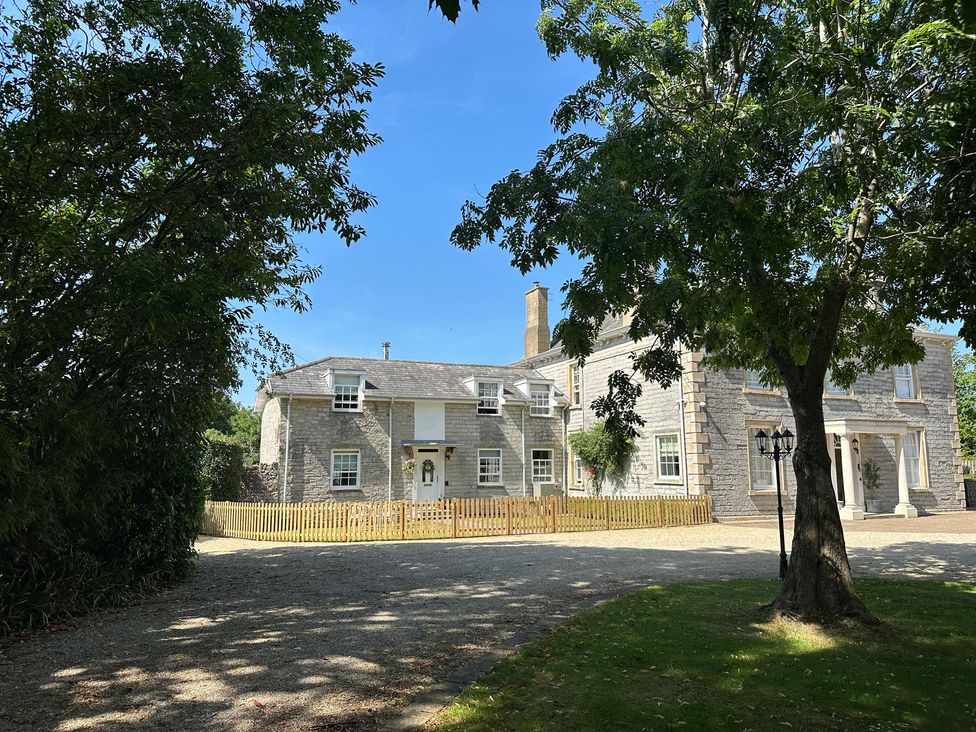A house with a fence and trees in the foreground at The Little Vicarage in Mark