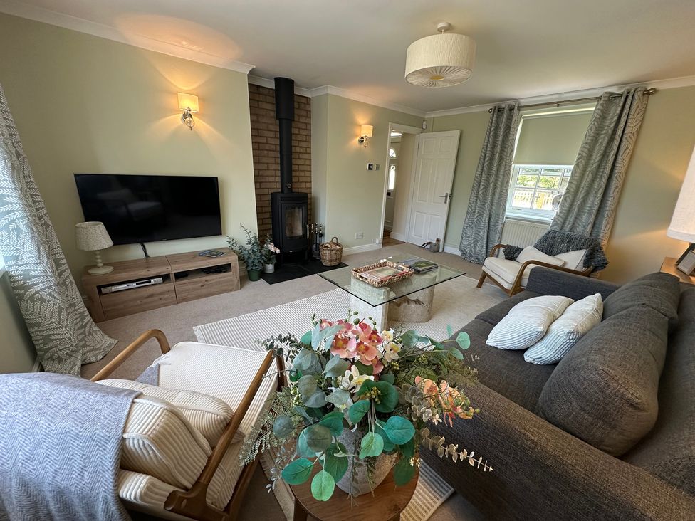 A living room with a television and a coffee table at The Little Vicarage in Mark