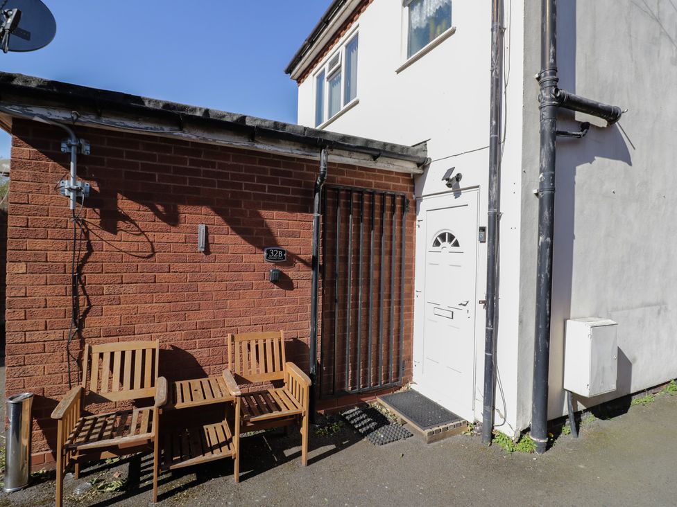An outdoor area with wooden chairs and a door at 32B Cramp Hill in Darlaston
