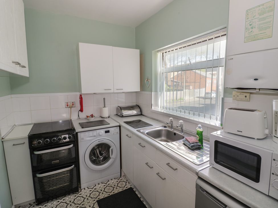 A kitchen with a cooker, washing machine, and sink at 32B Cramp Hill in Darlaston