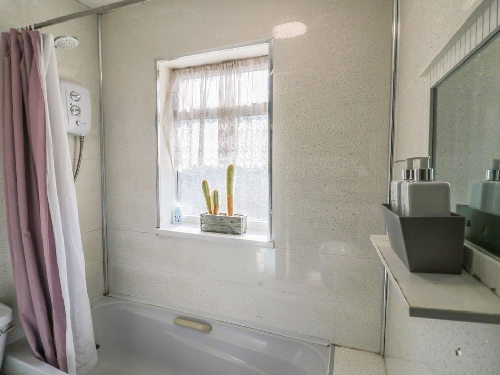 A bathroom with a bathtub and window at 32B Cramp Hill Darlaston