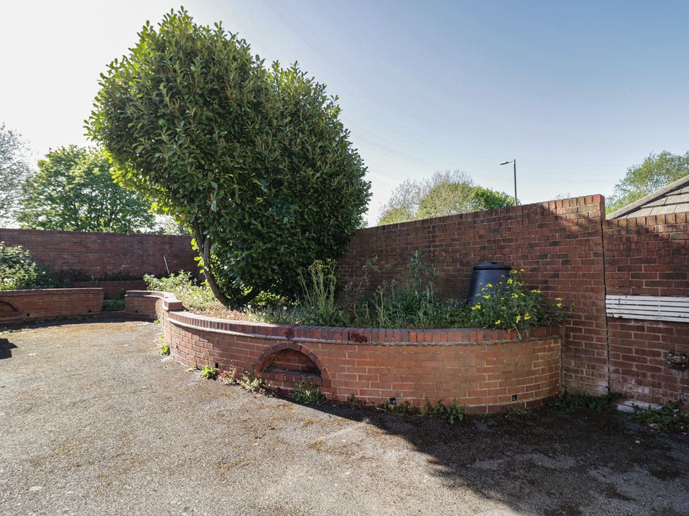 A garden with a brick wall and a bush at 32B Cramp Hill in Darlaston