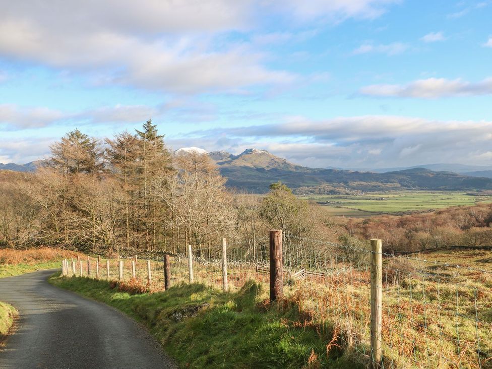 A road with a fence and trees in a mountain landscape at 2 Bryn Eglwys in Prenteg