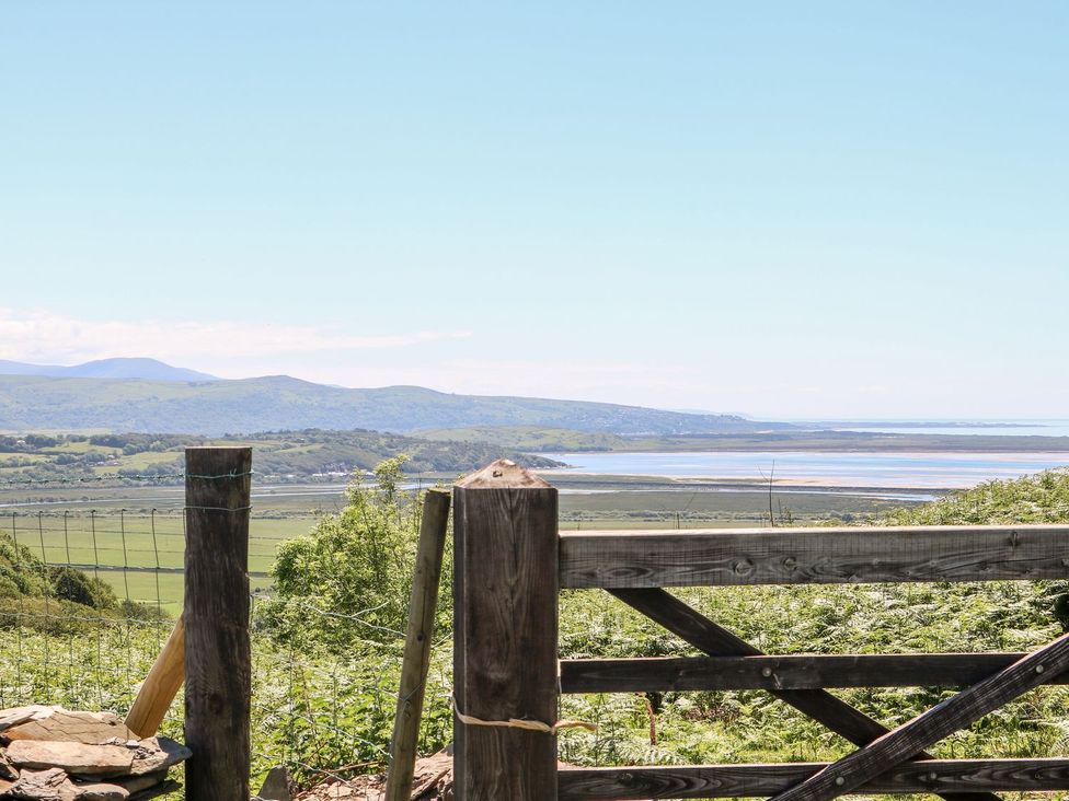 A landscape view with a wooden gate overlooking hills and water at 2 Bryn Eglwys Prenteg