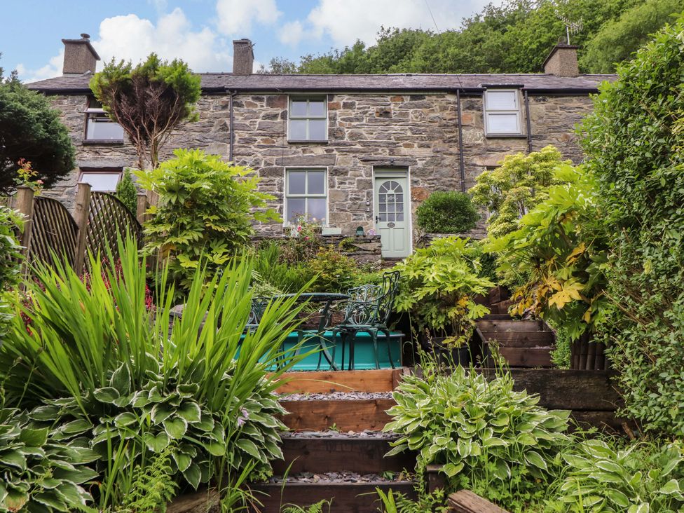 A garden with a stone house and plants at 2 Bryn Eglwys Prenteg