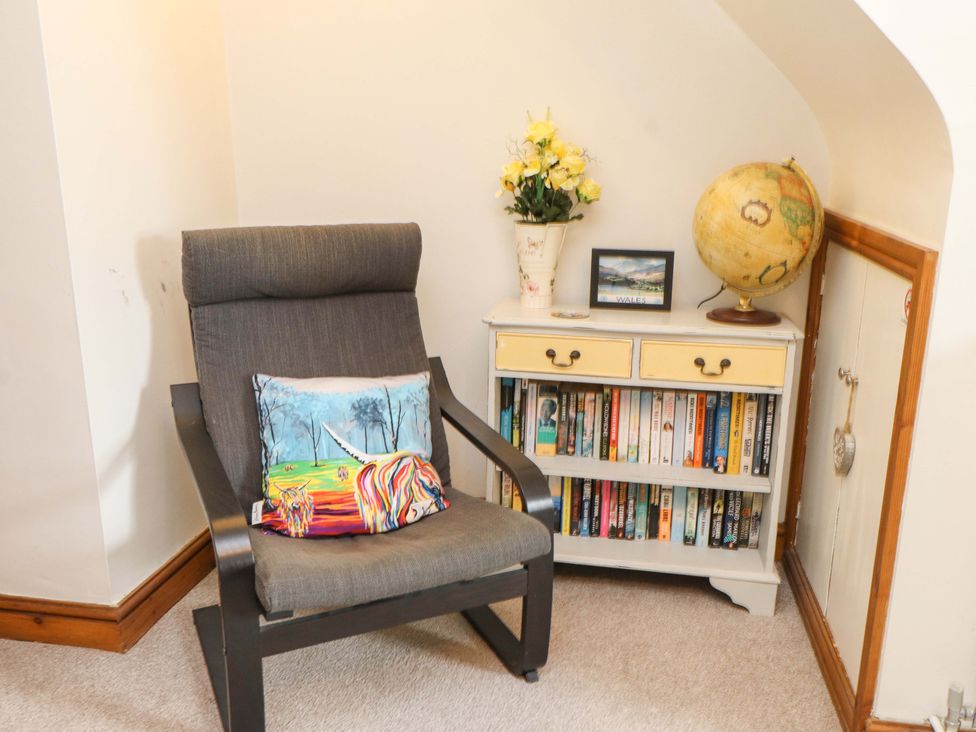 A corner with a chair, bookshelf, globe, and flowers at 2 Bryn Eglwys Prenteg