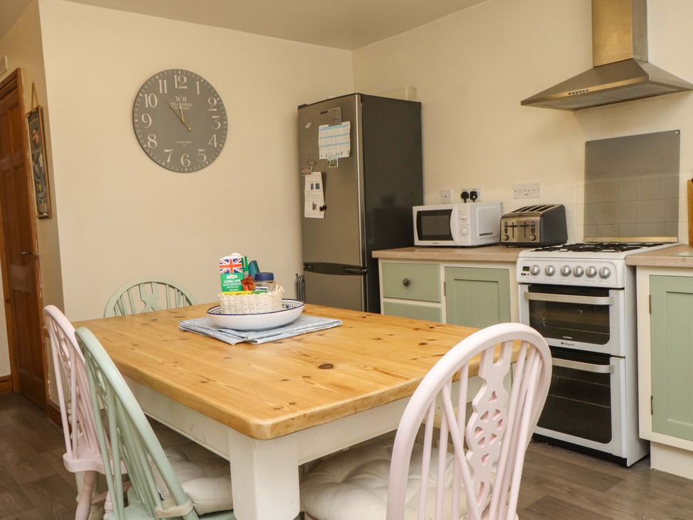 A kitchen with a dining table and chairs at 2 Bryn Eglwys in Prenteg