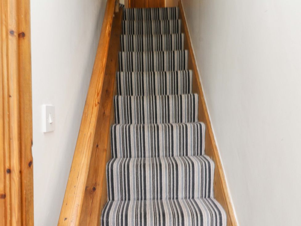 A staircase with striped carpet at 2 Bryn Eglwys in Prenteg
