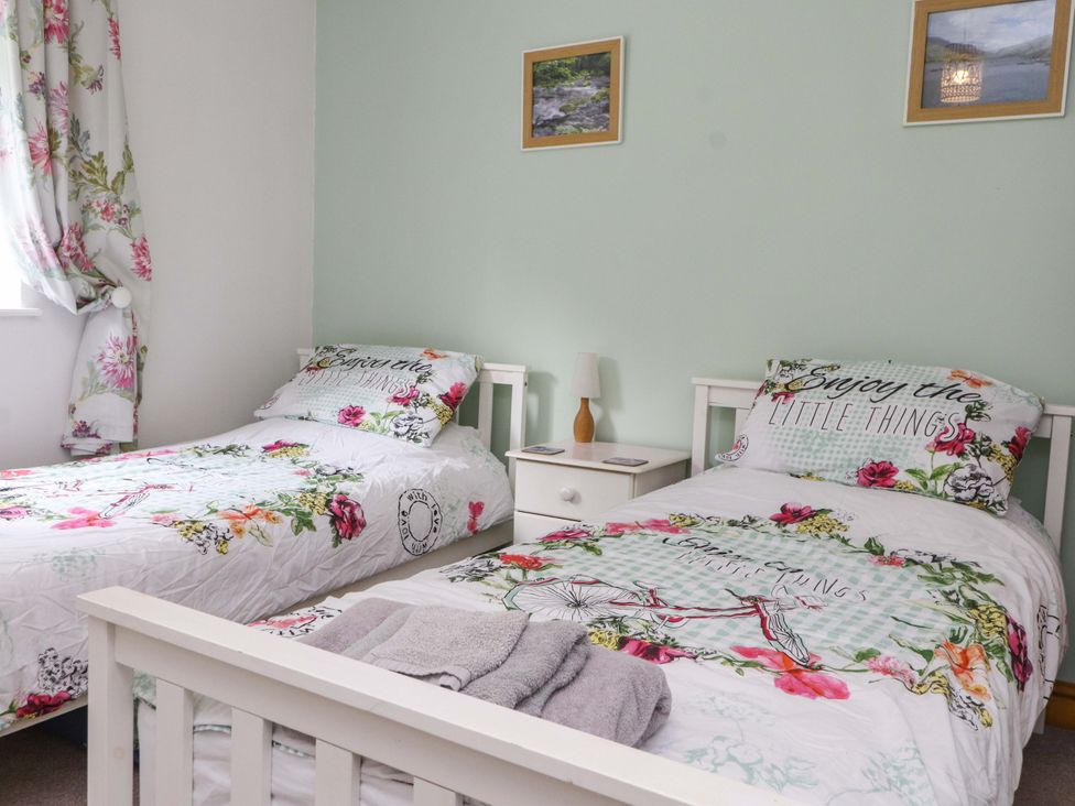 A bedroom with two beds and a bedside table at 2 Bryn Eglwys in Prenteg