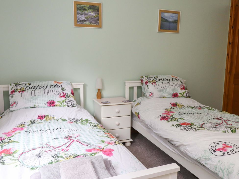 A bedroom with two single beds and a bedside table at 2 Bryn Eglwys Prenteg