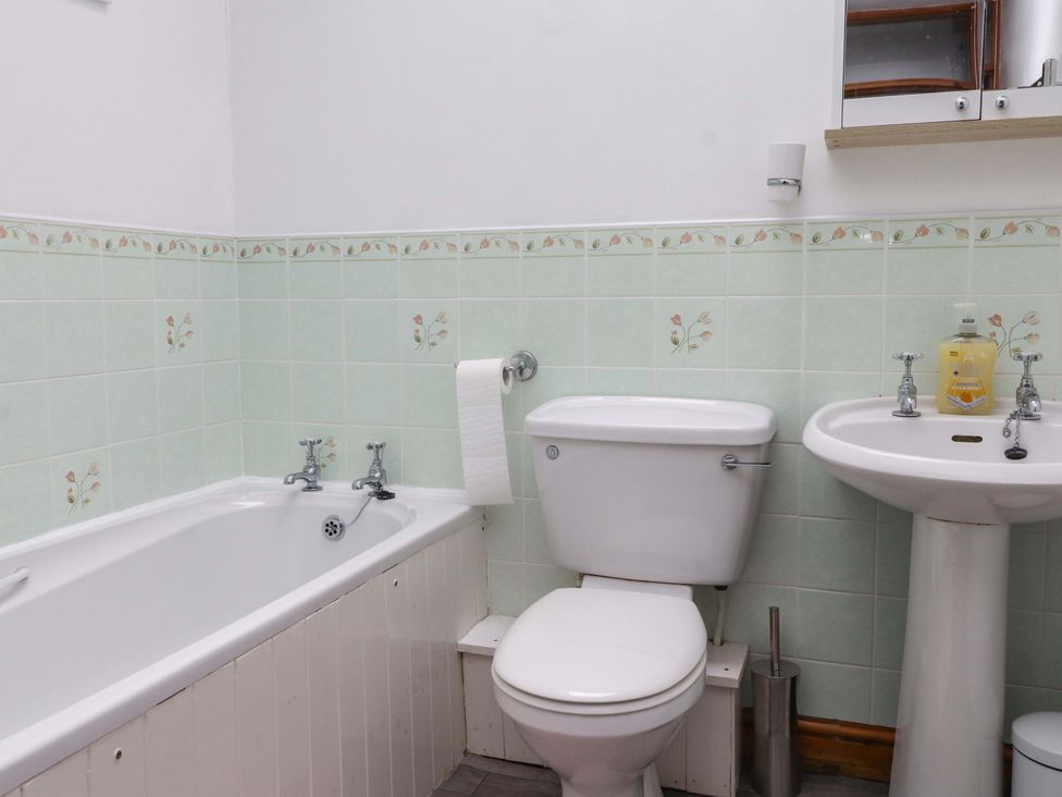 A bathroom with a bathtub, toilet, and sink at 2 Bryn Eglwys in Prenteg