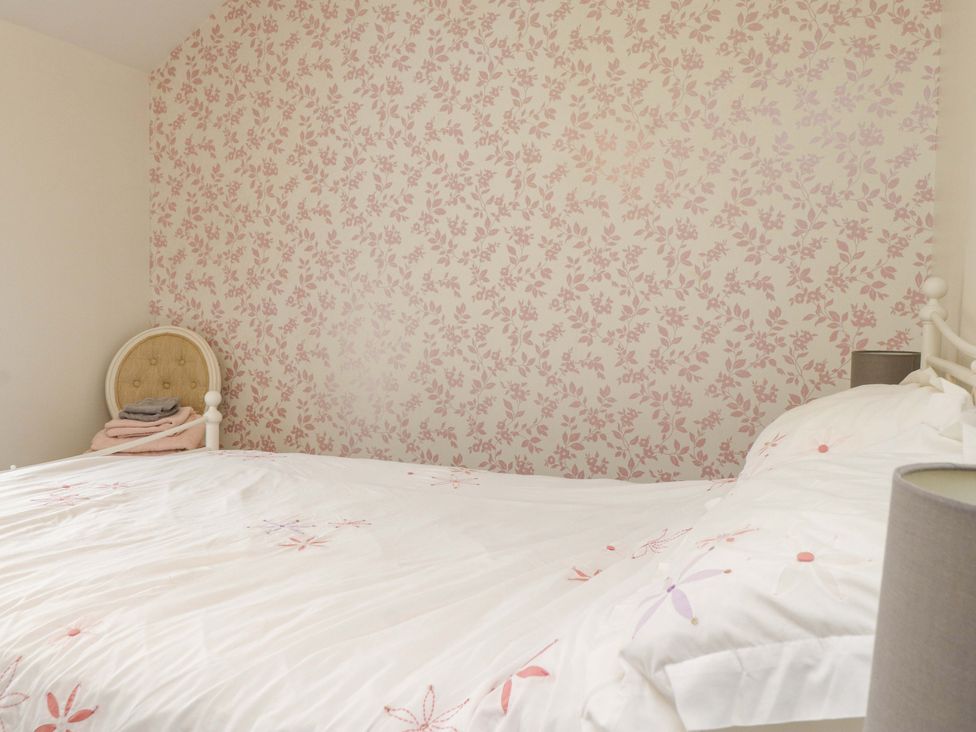 A bedroom with a bed and floral wallpaper at 2 Bryn Eglwys Prenteg