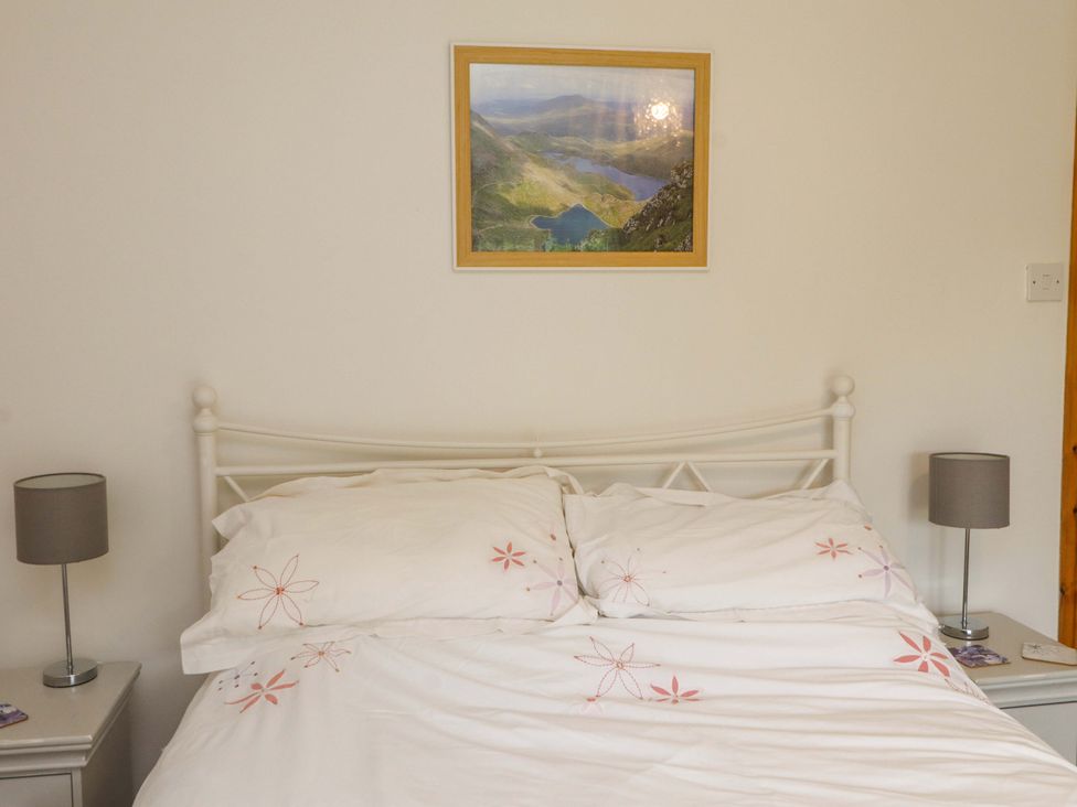 A bedroom with a bed and lamps at 2 Bryn Eglwys Prenteg