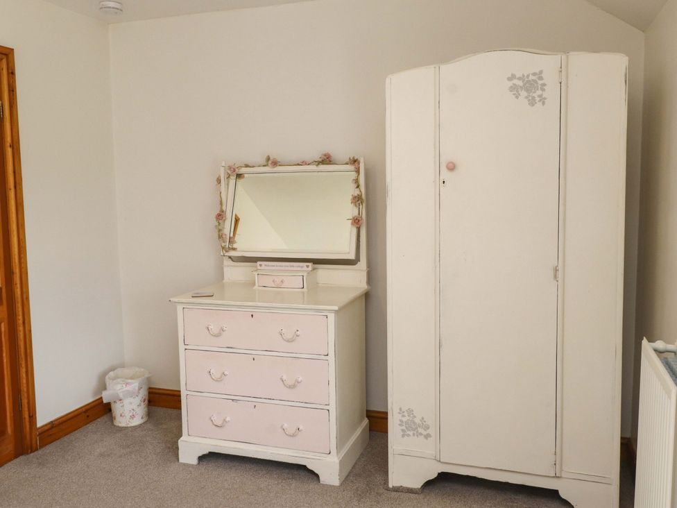 A bedroom featuring a dresser with a mirror and a wardrobe at 2 Bryn Eglwys in Prenteg