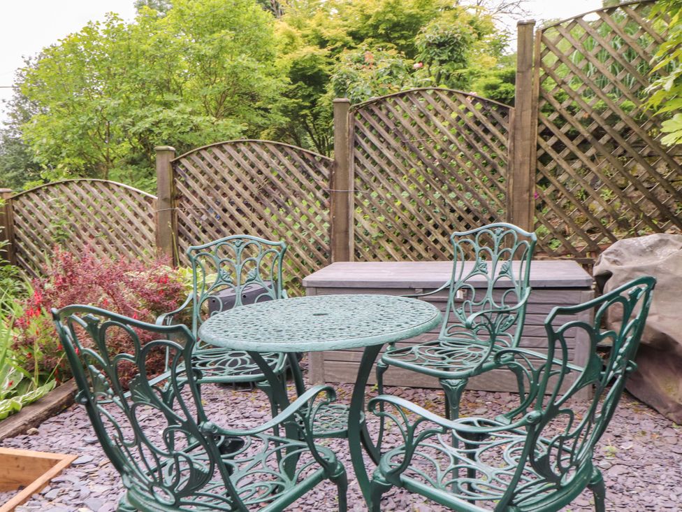 A garden with green chairs and a table at 2 Bryn Eglwys in Prenteg
