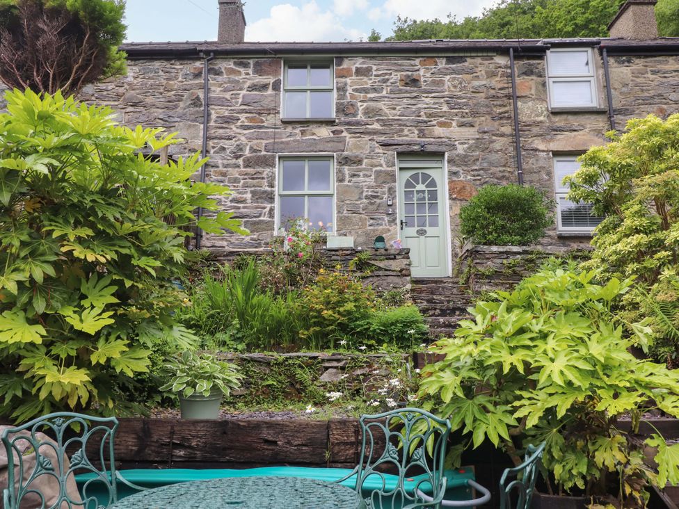 A garden with plants and a stone wall at 2 Bryn Eglwys in Prenteg