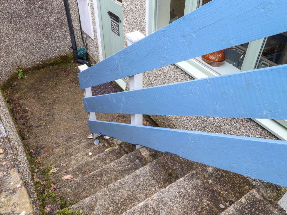 A staircase with a blue railing leading to a door at 2 Bryn Eglwys in Prenteg