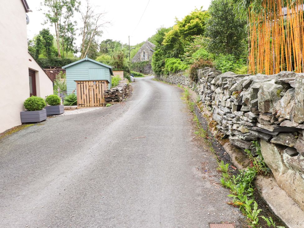 A road with a stone wall and a garden shed at 2 Bryn Eglwys in Prenteg