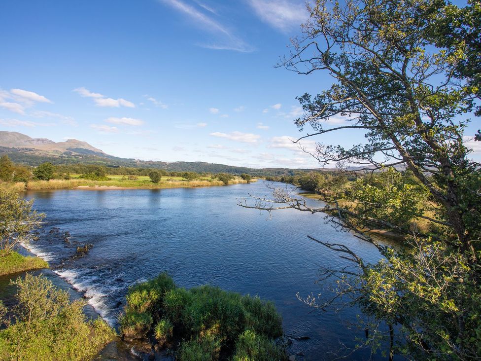 A river with trees and mountains in the background at 2 Bryn Eglwys in Prenteg near Porthmadog
