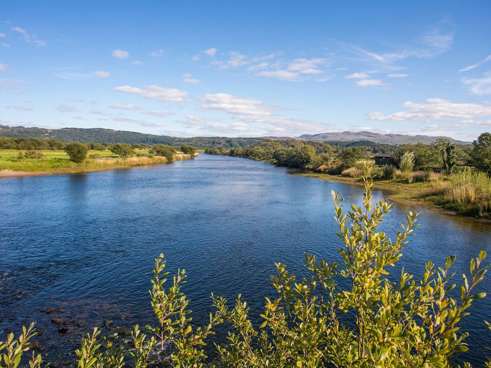 A river surrounded by trees and grass at 2 Bryn Eglwys Prenteg near Porthmadog