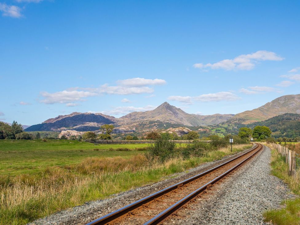A view of railroad tracks leading to mountains in outdoor landscape at 2 Bryn Eglwys Prenteg near Porthmadog