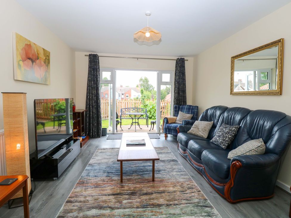 A living room with a sofa and television at The Mill House Gardens