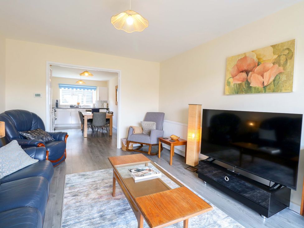 A living room with a sofa, coffee table, and television at The Mill House Gardens 