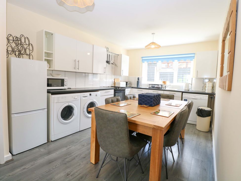 A kitchen with appliances and a dining table at The Mill House Gardens