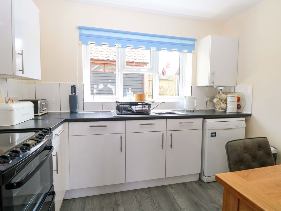 A kitchen with a sink, oven and window at The Mill House Gardens