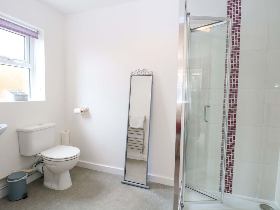 A bathroom featuring a toilet, mirror, and shower at The Mill House Gardens
