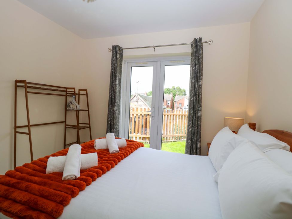 A bedroom with a bed and a sliding door at The Mill House Gardens