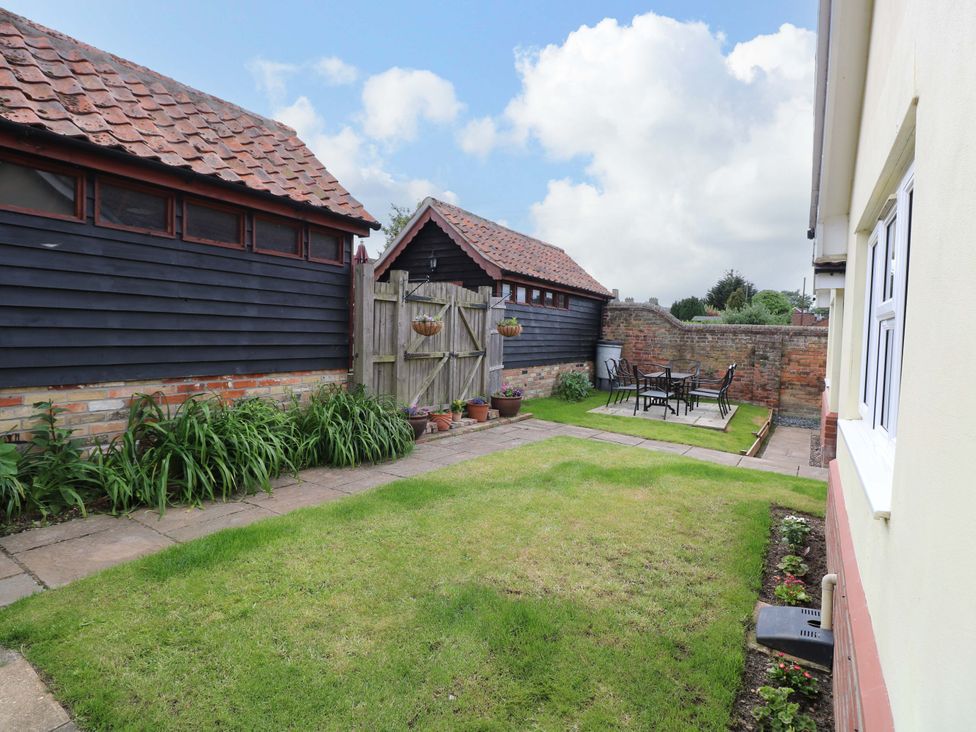 A garden with table and chairs surrounded by sheds at The Mill House Gardens